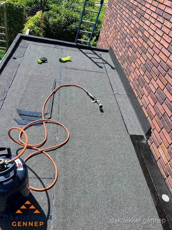 Plat dak met bitumen en brandgereedschap van dakdekkersbedrijf in Gennep