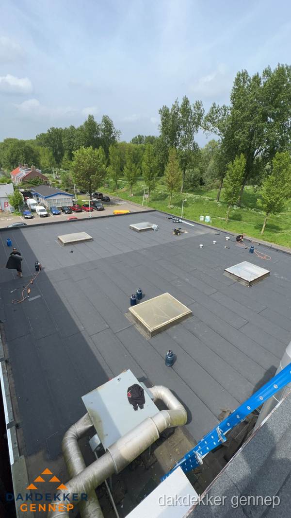Dakdekker aan het werk op groot plat dak met bitumen in Gennep
