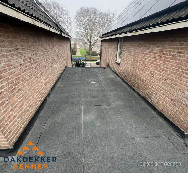 Plat dak met bitumen dakbedekking tussen bakstenen muren in Gennep